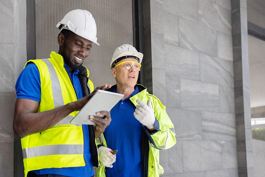 Specialized Business Insurance - Two Industry Engineers Use Digital Tablet to Discuss About Their Work at a Construction Site